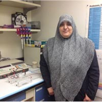 Samiha Benrabaa stands next to her lab bench.